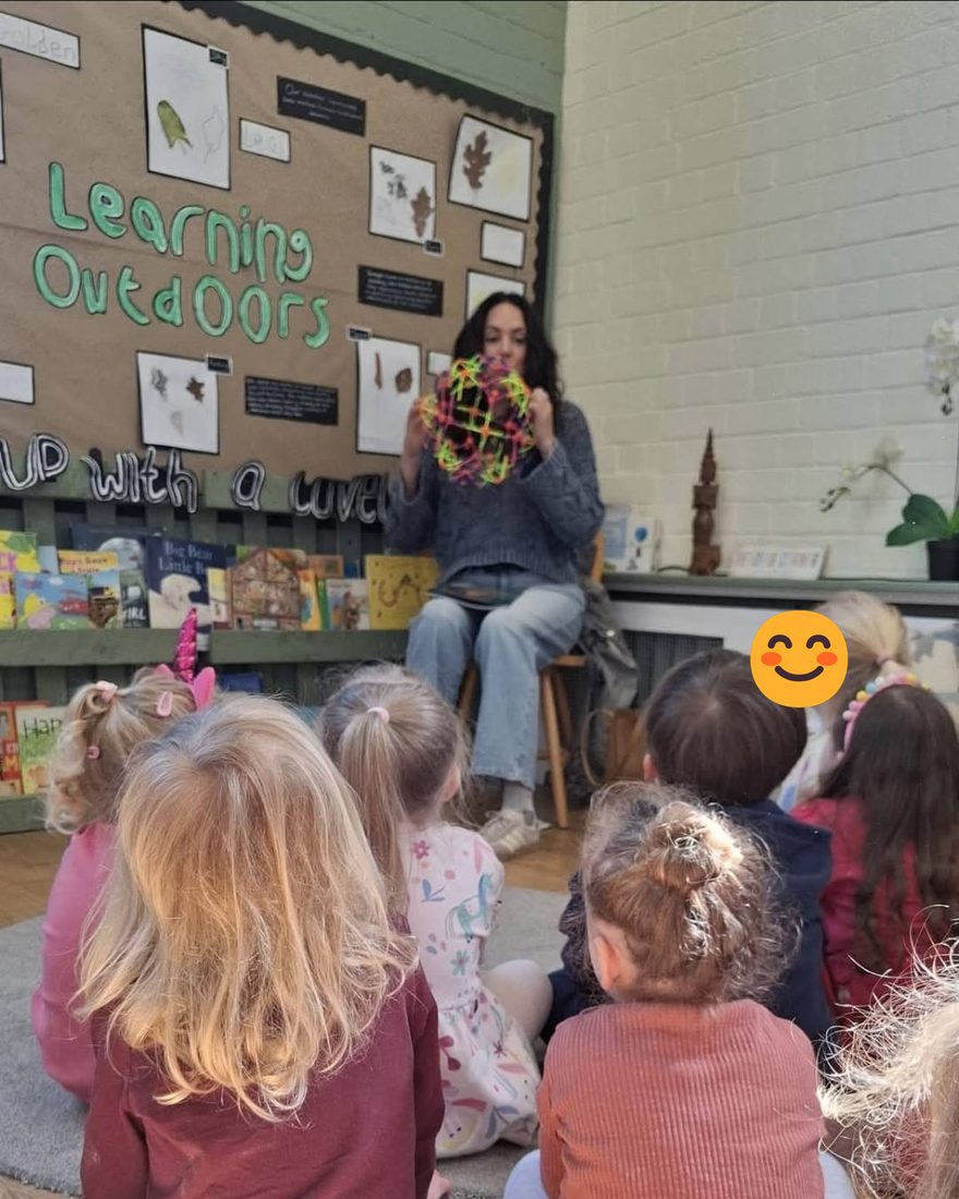 Natasha leading a breathing activity with a group of young children sitting on the floor