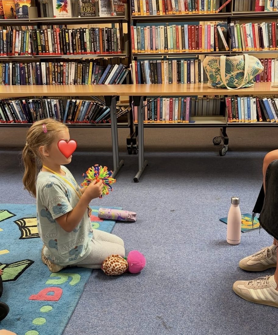 A child holding a colourful breathing ball during a library session